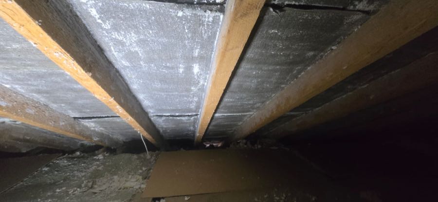 Spray foam insulation removal in progress on a UK roof, rafters exposed