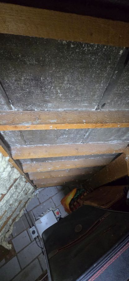 Original spray foam insulation before removal in a UK loft space