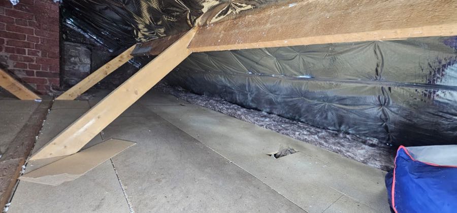 Original spray foam insulation before removal in a UK loft space